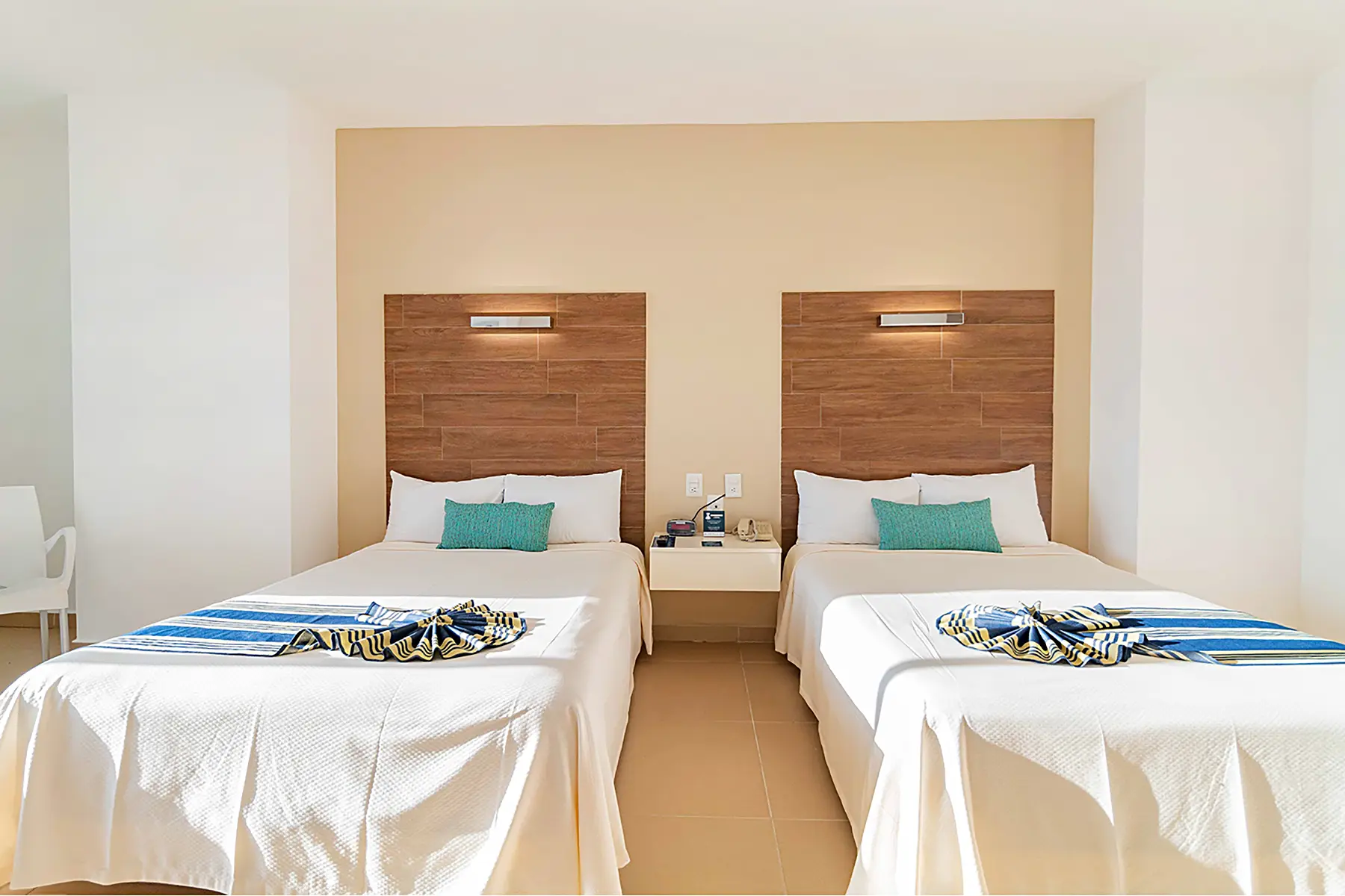 Habitación junior suite vista al mar con dos camas matrimoniales, televisión, mesa con dos sillas, mobiliario y luminaria de Hotel Pacific Palace Mazatlán